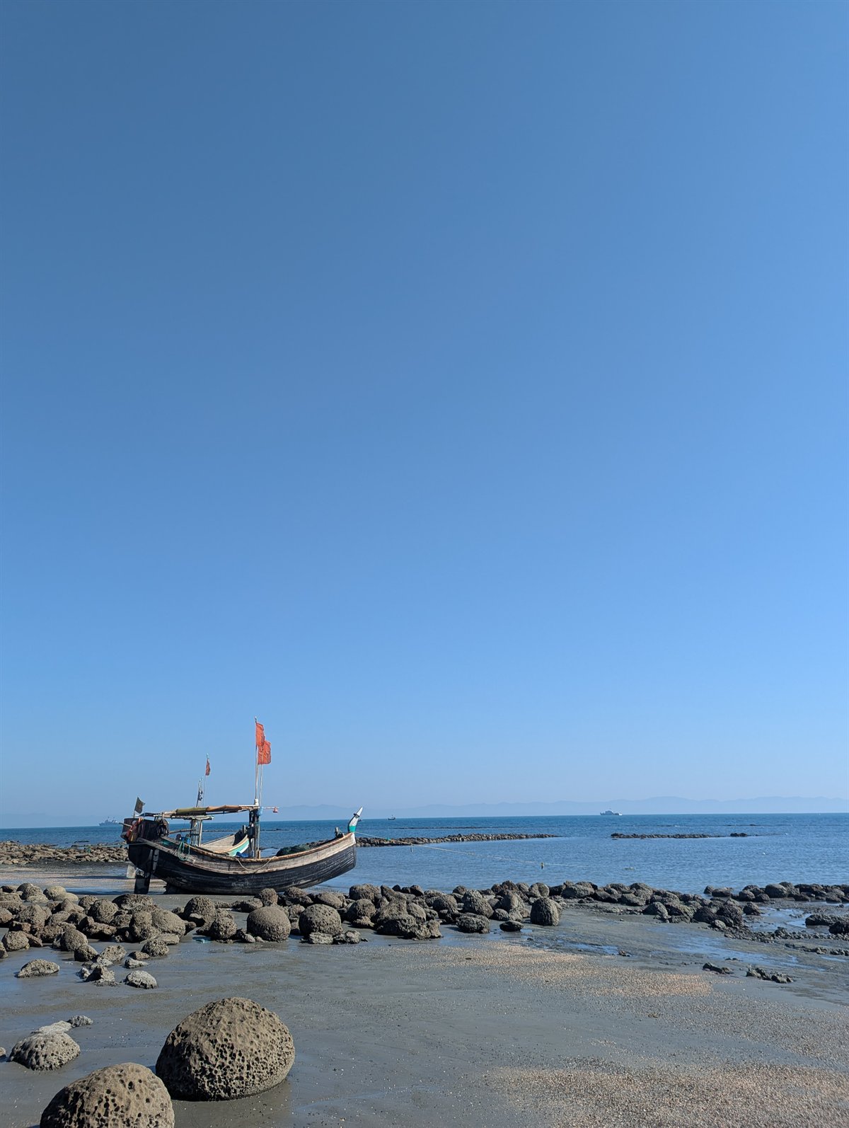 A fishing boat on the rocky shore of Saint Martin's Island under a clear sky